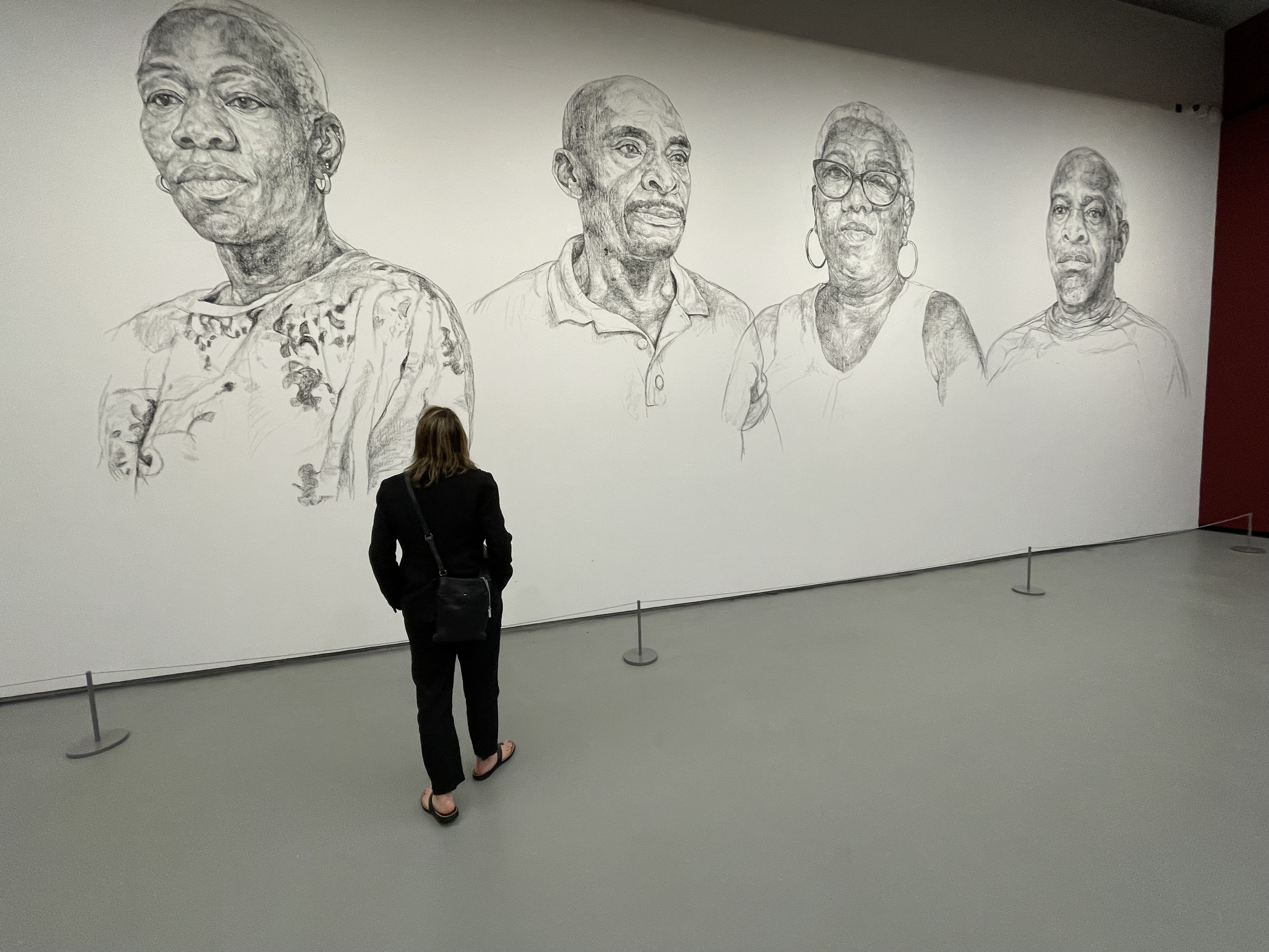 Jane, a normal sized human, in front of HUGE portraits by Turner Prize nominee Barbara Walker.