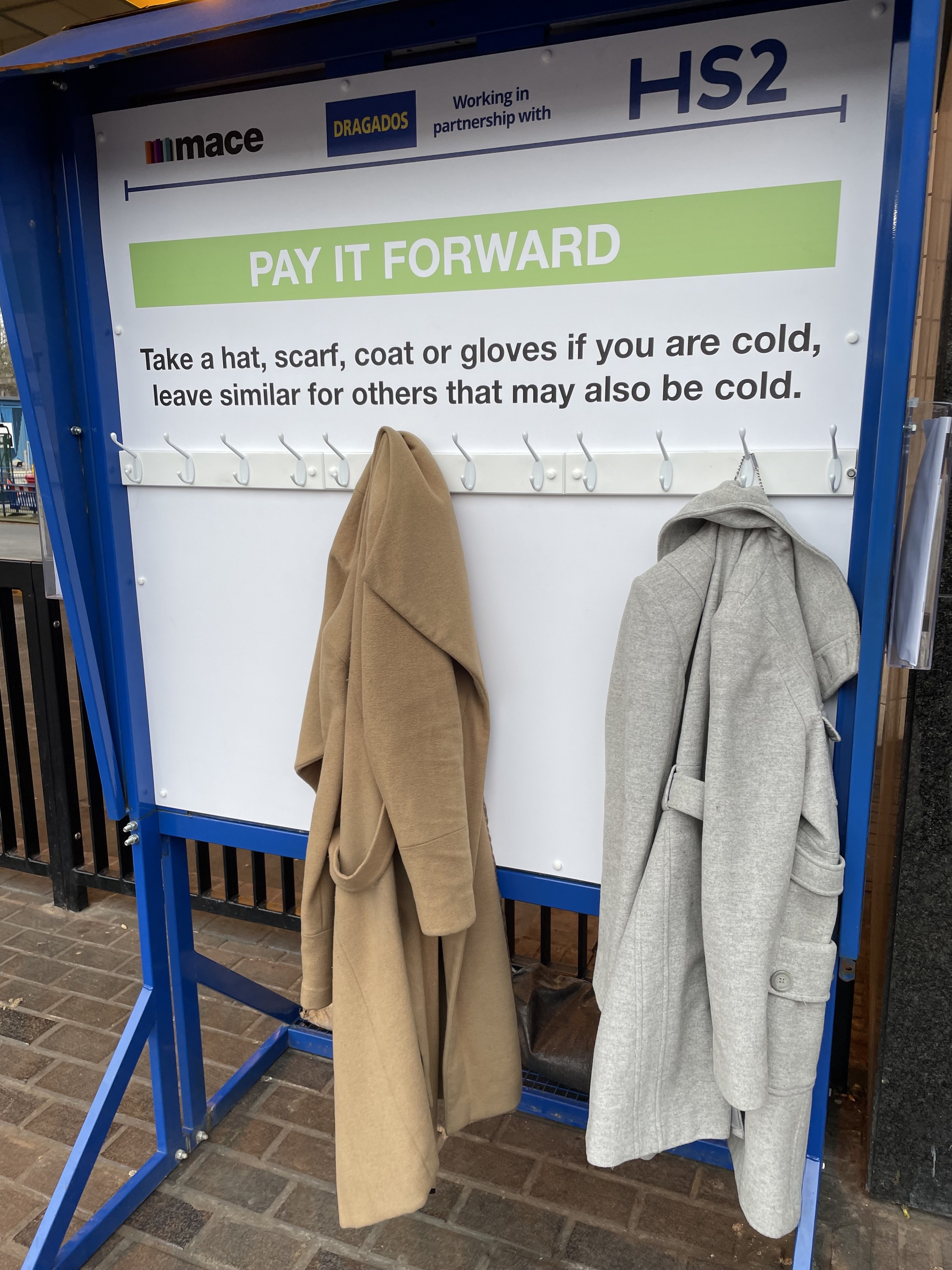 Costs hung up outside a train station. The sign reads:
PAY IT FORWARD
Take a hat, scarf, coat or gloves if you are cold, leave similar for others that may also be cold.